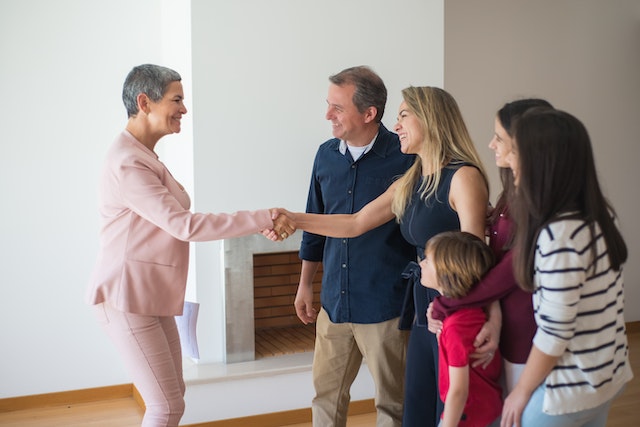 Property manager shaking hands with a woman who is standing next to the rest of her family of four